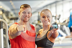 Happy man and woman pointing finger to you in gym