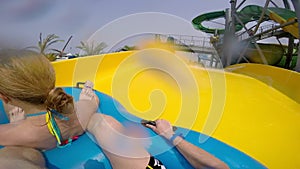 Happy man and woman riding down the water slide. People having fun in water park on resort during summer vacation