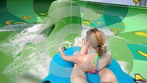 Happy man and woman riding down the water slide. People having fun in water park on resort during summer vacation