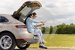 Happy man and woman with road map at hatchback car