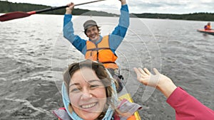 happy man and woman sail kayak waving hand to camera