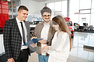Happy man and woman signing some documents with salesperson buying car