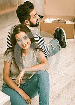 Happy man and woman sitting on the floor tired preparing to relocate to new apartment