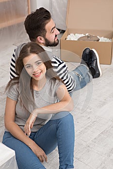 Happy man and woman sitting on the floor tired preparing to relocate to new apartment.