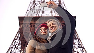 Happy man and woman smiling and posing for selfie in Paris, vacation memories