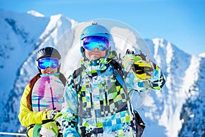 Happy man and woman snowboarders standing on snow resort against backdrop of mountain.