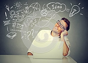 Happy man working on computer thinking dreaming has many ideas