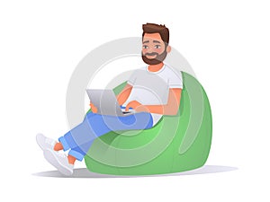 Happy man working on a laptop computer while sitting in a bean bag chair over isolated background. Freelancer guy working at home
