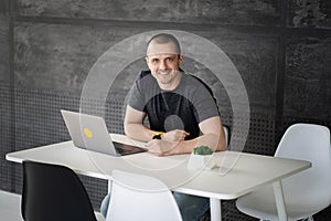 Happy man working on laptop in library or coworking office space