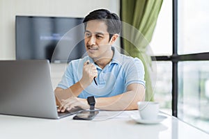 Happy man working online with laptop computer at home sitting at desk.