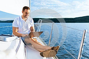 Happy Man On Yacht Sitting With Laptop Working On Sailboat