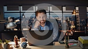 Happy manager reading computer in dark office closeup. Smiling man overworking