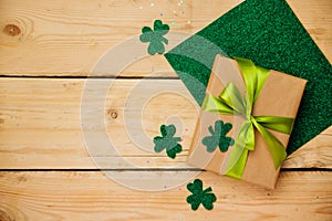 Happy March 17th. St. Patrick`s Day. Gift box wrapped in kraft paper, clover leaves on a wooden background