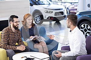 Happy marriage buying new car while talking with seller in a dea