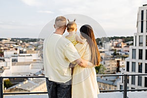 Happy married couple with daughter embracing on rooftop