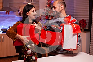 Happy married couple holding secret present gift with ribbon on it