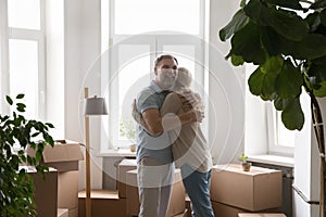 Happy married couple hugging at paper boxes at new home