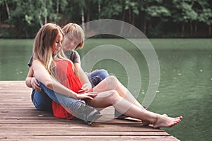 A happy married couple Husband hugs a beautiful adult pregnant wife. walks in a park by the lake. Holds her hands on her stomach.