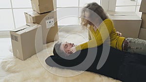 Happy married couple lays on carpet in new house and have fun