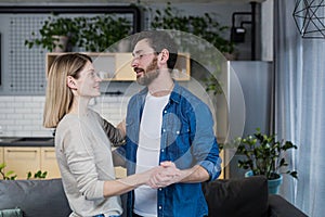 Happy married couple man and woman dancing together at home in the living room, having fun together