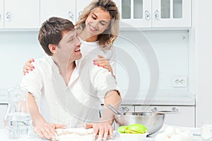 Happy married couple are preparing dinner in the kitchen and smiling. Husband and wife are preparing a birthday cake