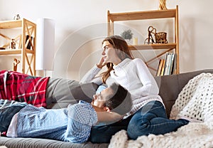 Happy married couple spending time together at home, indoors. Young man and woman sitting on sofa. Concept of family