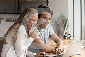 Happy married couple using laptop together at home workplace