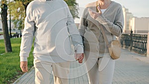 Happy married couple walking along city street hand-in-hand talking enjoying conversation on summer day