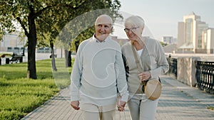 Happy married couple walking in city holding hands sightseeing enjoying day outdoors