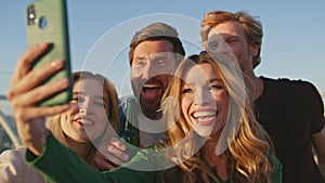 Happy mates making selfie smartphone celebrating at sunny rooftop close up.