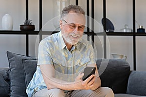 Happy mature 60s smartphone user reading text message on gadget