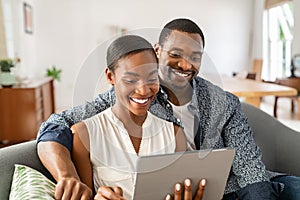 Happy mature african american couple using digital tablet at home