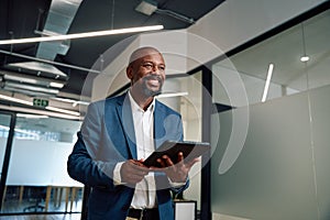 Happy mature black man in businesswear with digital tablet in corridor of office