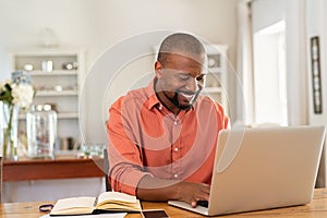 Happy mature black man using laptop
