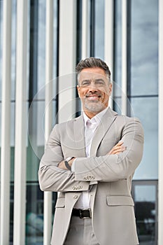 Happy mature business man wearing suit standing outdoor. Vertical portrait.