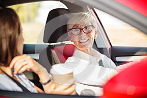 Happy mature business woman driving a car and talking to a young female colleague photo