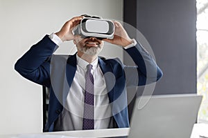 Happy Mature Businessman In VR Headset Having Fun At Workplace In Office