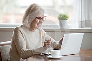 Happy mature businesswoman excited reading good news looking at photo