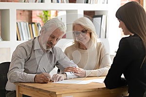 Happy mature clients sign contract closing deal with banker