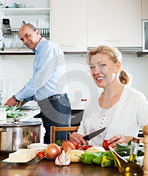 Happy mature couple cooking vegetables