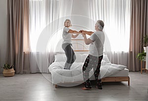 Happy mature couple dancing in bedroom