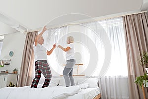 Happy mature couple dancing together on bed