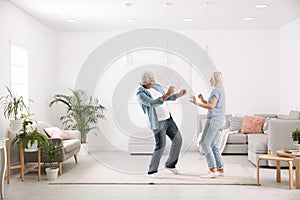 Happy mature couple dancing together in room