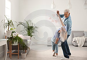 Happy mature couple dancing together in room