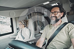 Happy mature couple driving and traveling together inside a camper van. Modern man and woman drive and enjoy motor home vehicle.