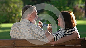 Happy mature couple eating ice-cream outdoors.