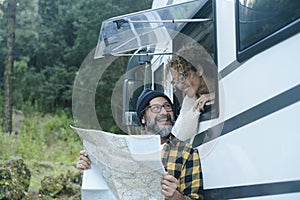 Happy mature couple enjoy vanlife camper vacation travel lifestyle talking and looking together a map guide to choose next holiday