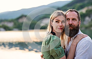 Happy mature couple in love hugging in nature, looking at camera.