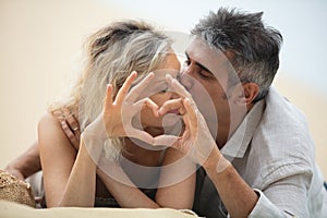 happy mature couple making heart sign and kissing