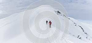 Senior couple is snowshoe hiking in alpine snow winter mountains panorama. Allgau, Bavaria, Germany.